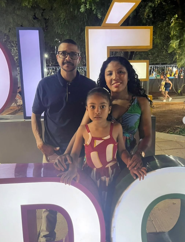 Fabiano e Eveline em frente ao letreiro de Fé